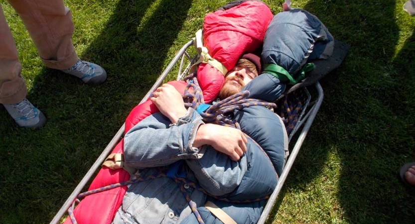 A person lays bundled in a stretcher during a wilderness first responder course